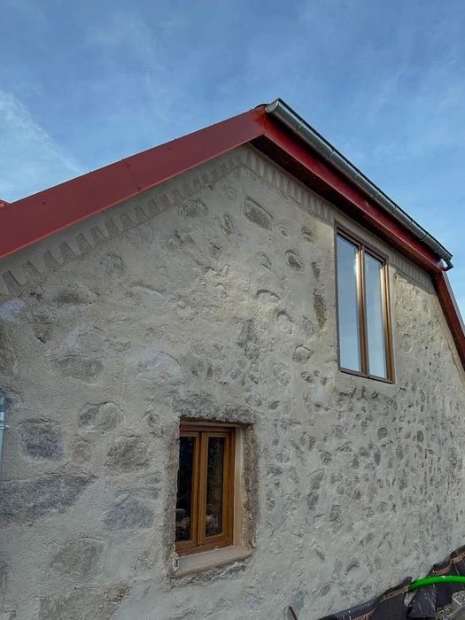 Façade en pierre naturelle apparente d'un bâtiment rénové, vue en contre-plongée