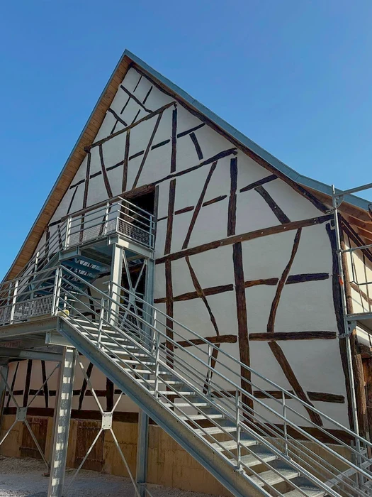 Façade en colombage d'un bâtiment historique rénovée, structure à pan de bois apparents sombres sur enduit blanc