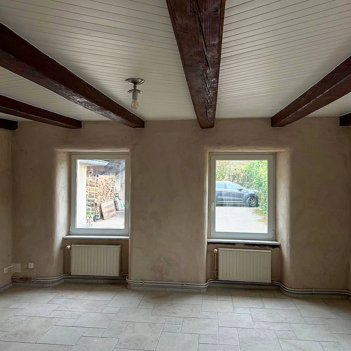 Salle rustique vide avec banquette en chêne massif à panneaux encastrés longeant le mur