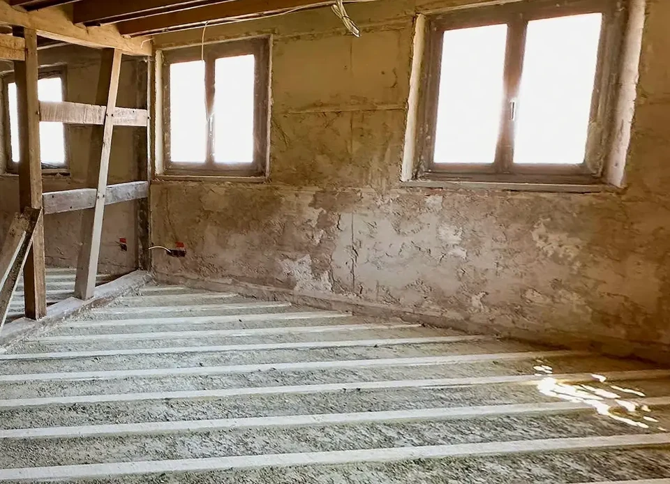 Chantier de rénovation extérieur avec ouvrier en salopette bleue travaillant sur échafaudage tubulaire