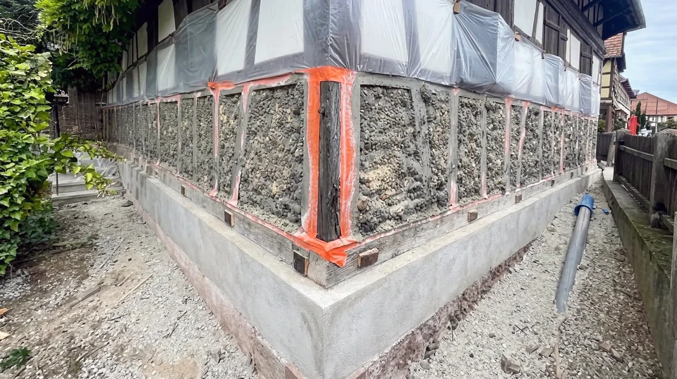 Facade latérale d'une maison individuelle de plain-pied, enduit blanc lisse avec chaîne d'angle en pierre reconstituée apparente