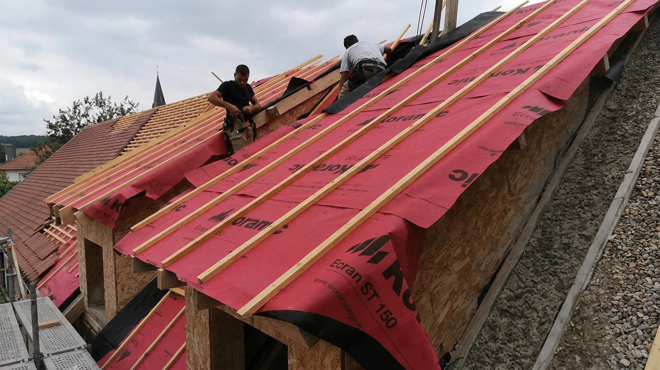 Ouvriers en équipements de sécurité haute visibilité effectuent des travaux d'étanchéité sur toiture-terrasse d'immeuble